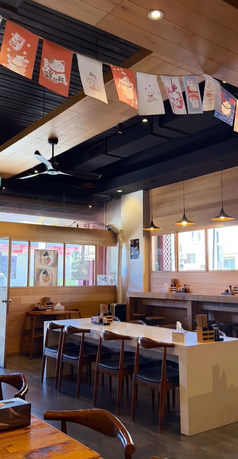 The empty Ramen Ryoma dining room in Cabramatta: timber tables, a long white counter and paper flags along the ceiling
